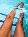 Young womanÃ¢â¬â¢s long tan legs in bright blue pool water